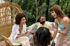 Young friends laugh and bond over drinks at a cozy outdoor cafe surrounded by nature