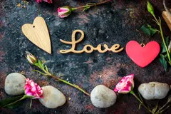 Amidst a rustic backdrop, delicate roses and smooth stones frame a heartfelt expression of love, inviting emotions of warmth and connection