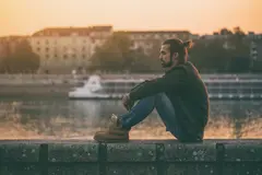 Depressed modern businessman sitting by the river