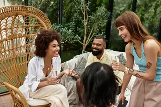 Young friends laugh and bond over drinks at a cozy outdoor cafe surrounded by nature